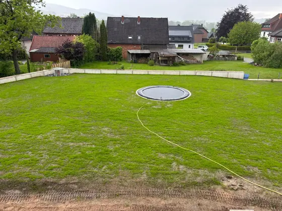 Derselbe Garten mit frischem Rasen und eingelassenem Trampolin