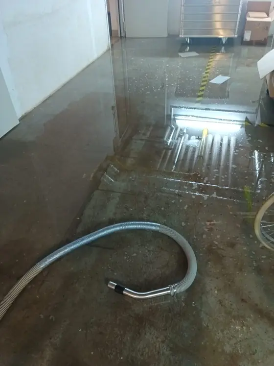 Saugschlauch auf einem nassen Boden beim Absaugen von Wasser