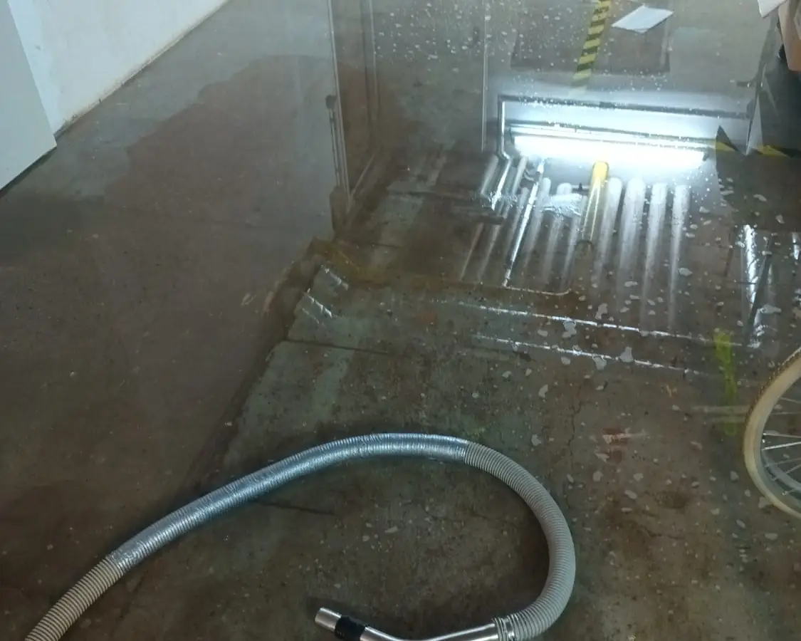 Nasser Boden nach einem Wasserschaden, ein Saugschlauch liegt bereit