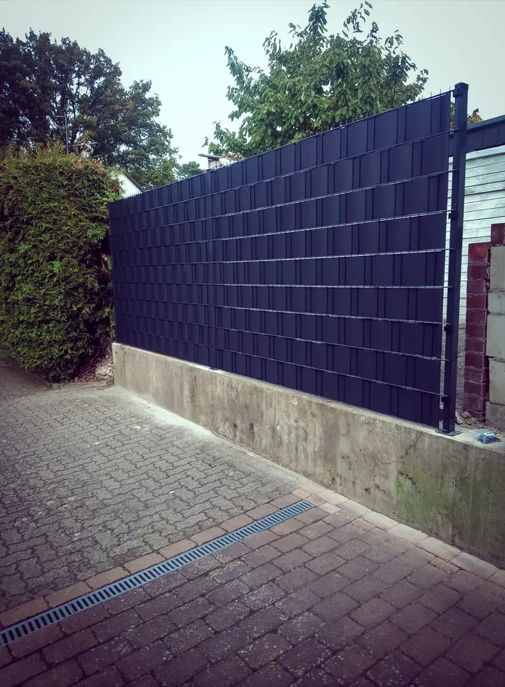 Neu montierter Doppelstabmattenzaun mit anthrazitfarbenem Sichtschutz an einer Hofeinfahrt